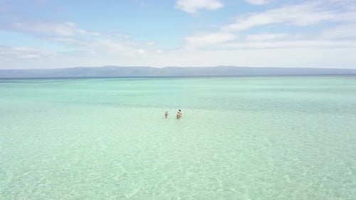 Aerial Cinematic Group of Tourists Standing and Swimming in the Beach Resort