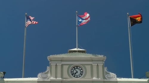 Flags Waving atop a Historic Building on a Clear Day