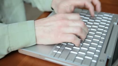Typing on Laptop Keyboard at Wooden Table