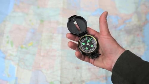 Hand Holding a Compass in front of Map