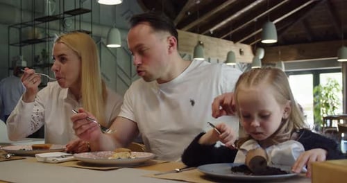 Young Family With A Little Girl Eating Dessert In A Cafe
