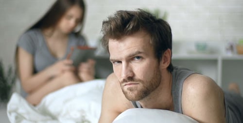 Frustrated Man with Woman on Tablet in Bed