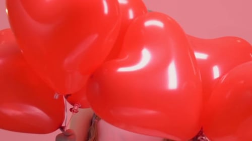 Little Girl Smiling Holding Heart Balloons