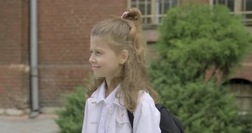 Girl Primary School Student with Backpack Walking Near School Building