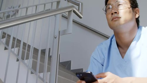 Medical Professional Using Smartphone in Hospital Stairwell