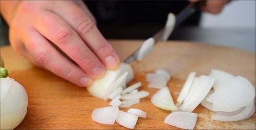 Hands Slicing an Onion with a Knife