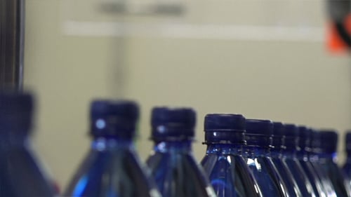 Blue Bottles Travel Along Production Line