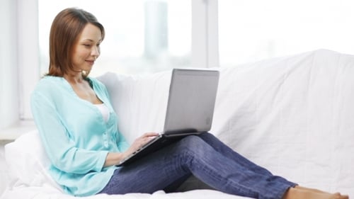 Woman Relaxes on Couch with Laptop