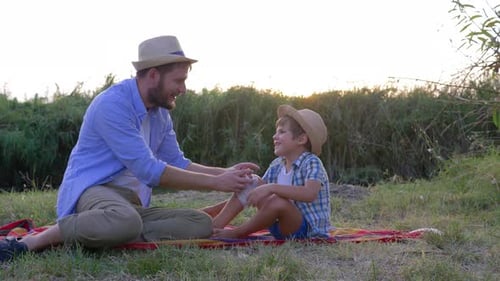 Loving Father Bandaging Son's Knee Outdoors