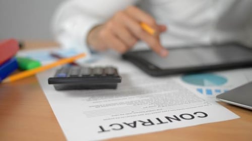 Businessman Reading on Tablet Pc and Calculating