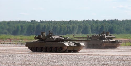 Two Green Military Tanks Moving Across an Open Field