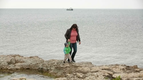 Mother and Child Walking on Rocky Coastline