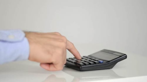Hand Using Calculator on White Table