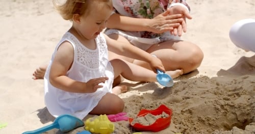 Niña jugando con juguetes de arena en la playa