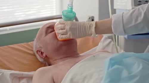 Senior Patient Receiving Oxygen Mask in Hospital Bed