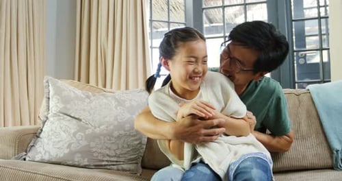 Dad Hugging Laughing Daughter on Couch