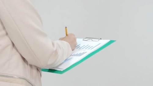Person Writes on Data Graph on Clipboard