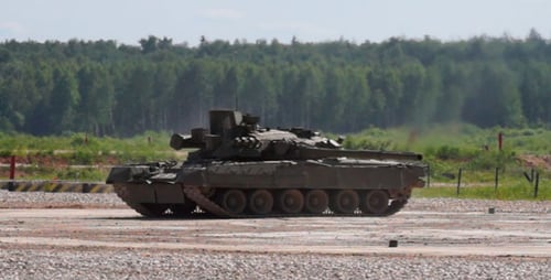 Two Military Tanks Stationary on Gravel Lot