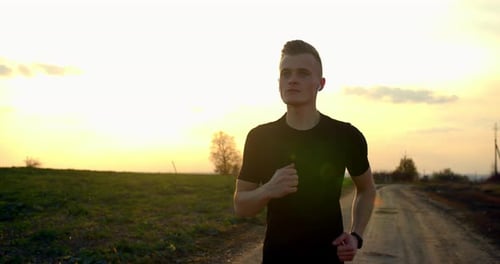 Young Guy Is Running Off-road at Sunset in Autumn Weather
