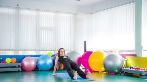 Woman Exercising on Yoga Mat in a Sunny Gym
