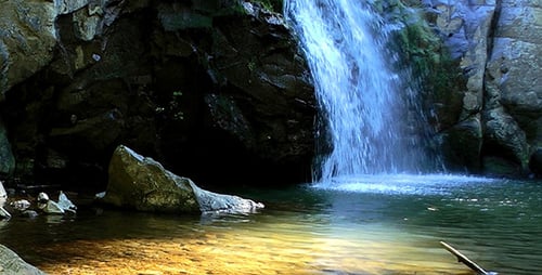 Waterfall Cascading Into Pool Surrounded By Rocks
