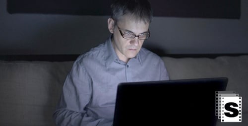 Man Using Laptop Computer Late at Night Indoors