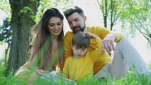 Happy Family Together in the Park Reading