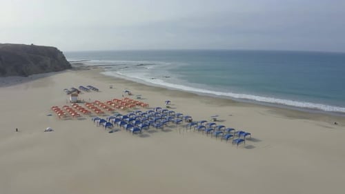Aerial view of a empty beach filled with blue and red beach tents