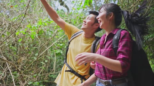 Young Asian man and woman friend or couple traveling walking with happiness in the forest together.