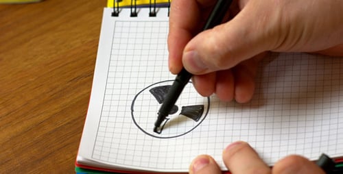 Drawing Radiation Symbol in Notebook with Black Marker