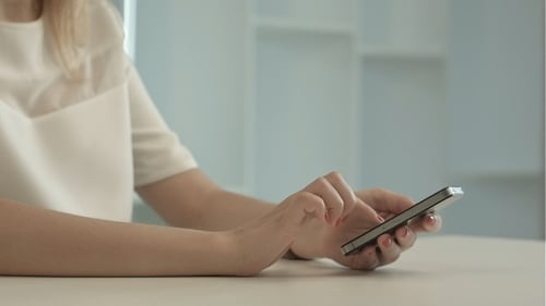 Woman Types on Mobile Phone Indoors