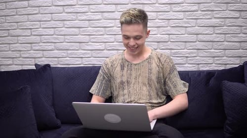 Young Adult Using Laptop on Sofa Indoors