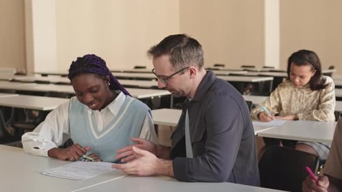Professor Helping Students with Homework in Classroom