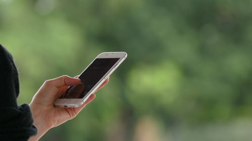 Hand Holds and Swipes a Phone Outdoors