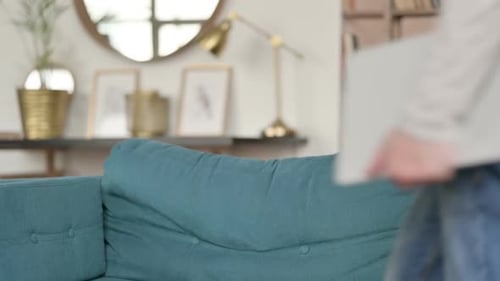 Man Sitting on Couch Opening Laptop