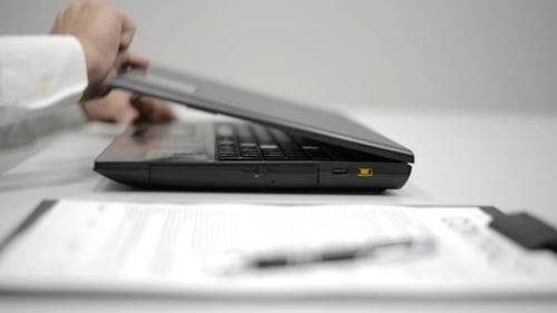 Person Opens Laptop and Types in Office