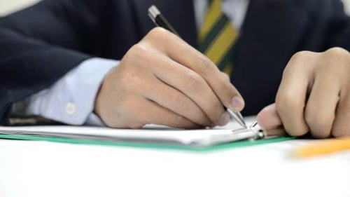 Adult Writes on Paper with Pen in Office