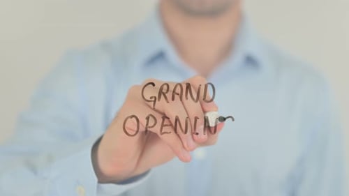 Grand Opening Written by Man in Light Blue Shirt