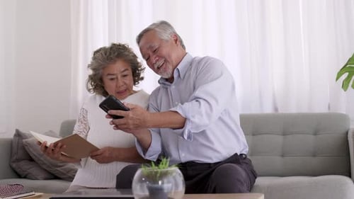 Senior Couple Laughing with Smartphone in Living Room