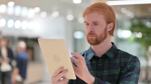 Man With Red Hair Uses Tablet in Office