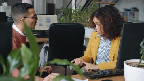 Arab Man and African American Woman Talking and Laughing at Desk in Office
