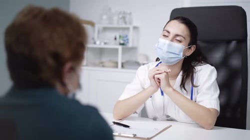 Physician sharing document and speaking with unrecognizable patient in clinic