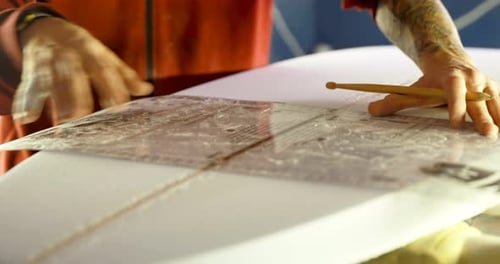 Shaper Adjusts Ruler on Surfboard
