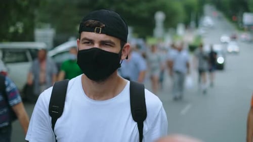 Man in Mask Walking on City Street