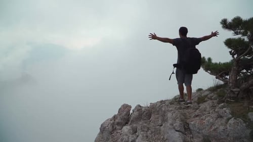 The Guy Comes To the Edge of the Mountain and Raises His Hands Up