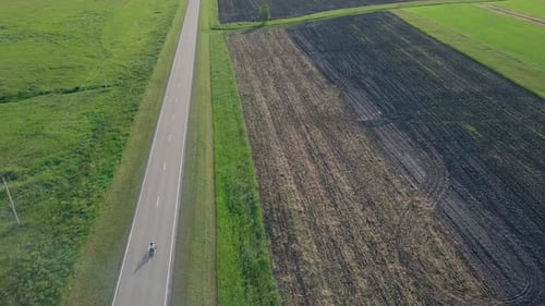 Upper View People on Motorbike Drives Along Gray Road