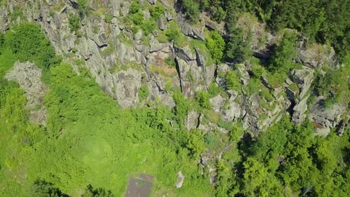 Luftbild: Fliegen mit drehbarer Kamera. Blick auf den Fuß eines Steinberges mit Nadelwald