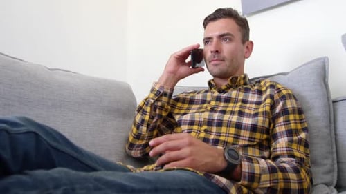 Young Man Talking on Smartphone on Couch