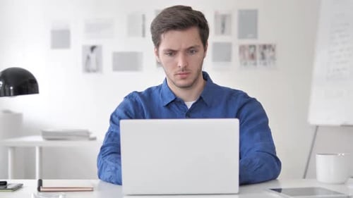 Young Adult Working on Laptop in Bright Office