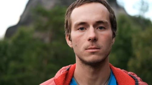 Zeitlupenporträt eines jungen männlichen Wanderers, der in die Kamera schaut und lächelt